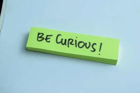 Concept of Be Curious write on sticky notes isolated on Wooden Table. Stock Photos