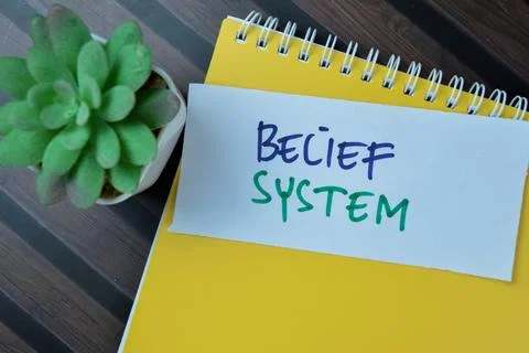 Concept of Belief System write on sticky notes isolated on Wooden Table. Stock Photos