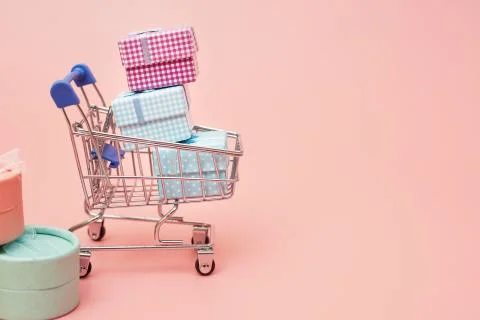 Concept black friday, gift boxes with shopping cart on pink pastel background Stock Photos