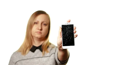 The concept of a broken gadget. Frustrated and tired middle-aged woman holding a Stock-Footage 103564253