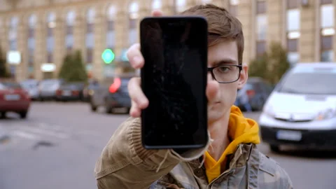 The concept of a broken gadget. Frustrated young man shows a smartphone with a Stock Footage 106142764