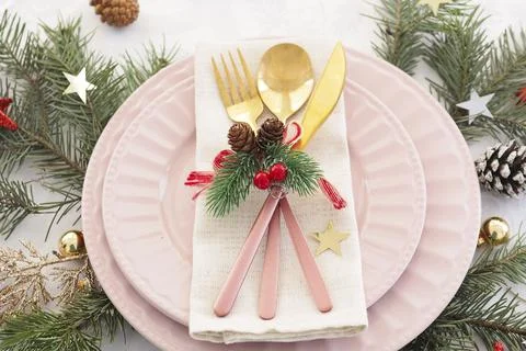 Concept of christmas table setting. two pink plates, cutlery, fir branches, c Stock Photos