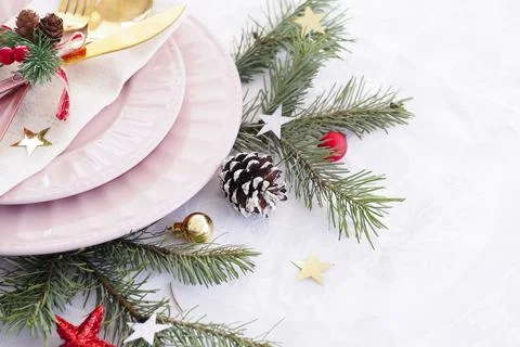 Concept of christmas table setting. two pink plates, cutlery, fir branches, c Stock Photos