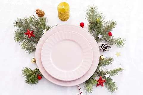 Concept of christmas table setting. two empty pink plates, fir branches, cone Stock Photos