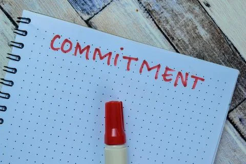 Concept of Commitment write on book isolated on Wooden Table. Stock Photos