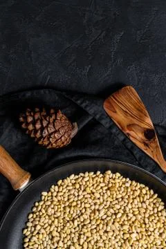 Concept of cooking roasted pine nuts in a frying pan. Black background. Top view Foto stock
