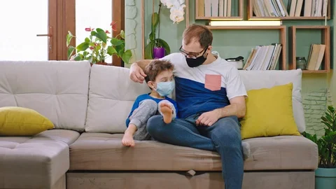 Concept of Coronavirus dad with his small son on the sofa stay home in Stock Footage 127712701