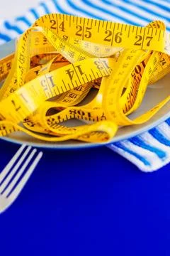 The concept of the diet. The fork rewound centimeter lying on plate closeup Stock Photos