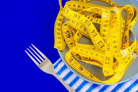 The concept of the diet. The fork rewound centimeter lying on plate closeup Stock Photos