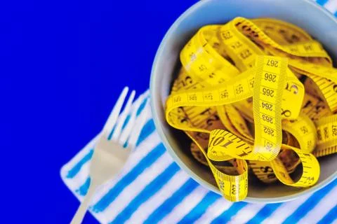 The concept of the diet. The fork rewound centimeter lying on plate closeup Stock Photos