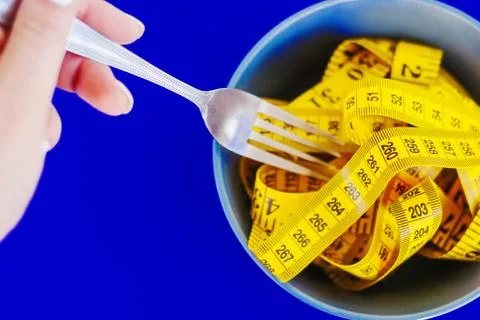 The concept of the diet. The fork rewound centimeter lying on plate closeup Stock Photos