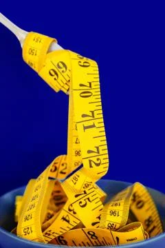 The concept of the diet. The fork rewound centimeter lying on plate closeup Stock Photos