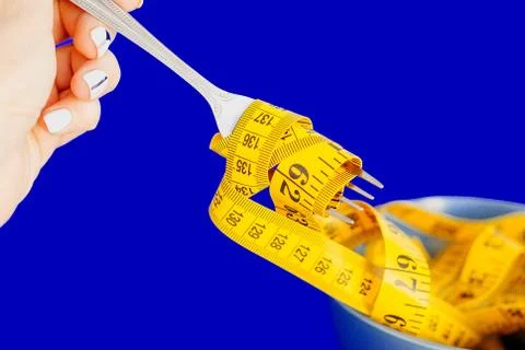 The concept of the diet. The fork rewound centimeter lying on plate closeup Stock Photos