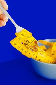 The concept of the diet. The fork rewound centimeter lying on plate closeup Stock Photos
