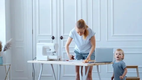 Concept during self-isolation and quarantine. A woman with a small child sews a Stock Footage 127737800