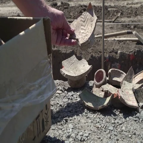 Concept - dust of ages and time. Archaeologist blowing dust with ancient shards. Stock Footage 69440108
