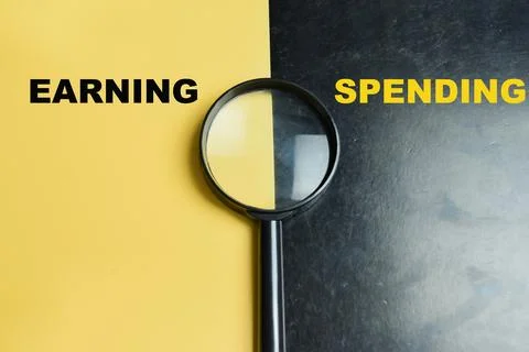 Concept of earning or spending write on color background with magnifying glass Stock Photos