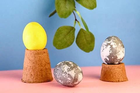 Concept of Easter. Eggs on a podium made of peat pots with a pink and blue Stock Photos