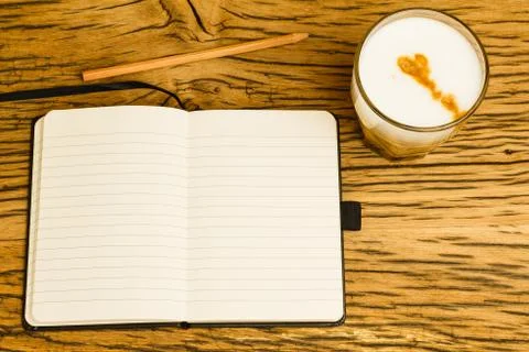 Concept empty notebook with pencil, start of the day. Coffee on oak desk. Stock Photos