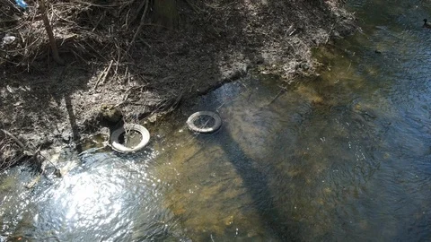 Concept of environmental pollution by throwing a old tyre in the river. Stock Footage 107694679