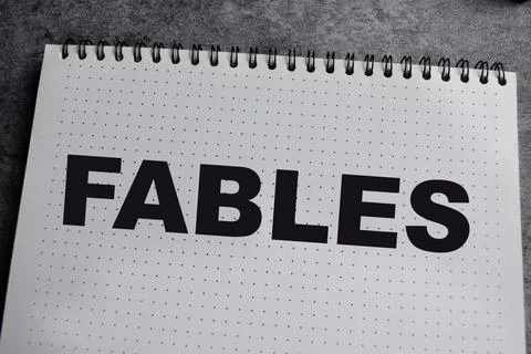 Concept of Fables write on book isolated on Wooden Table. Stock Photos