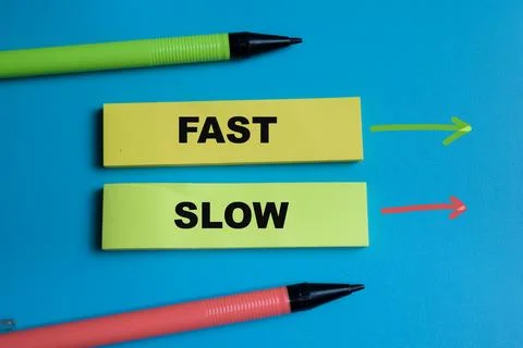 Concept of Fast or slow write on sticky notes isolated on Wooden Table. Stock Photos