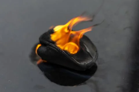 Concept of fire safety. Burning wireless computer mouse on a black table. Stock Photos