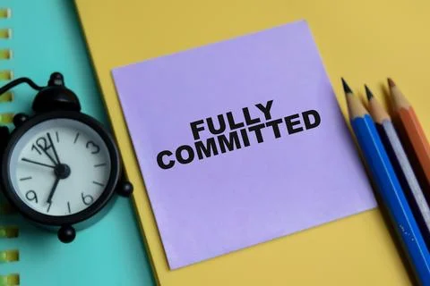 Concept of fully committed write on clipboard isolated on Wooden Table. Stock Photos