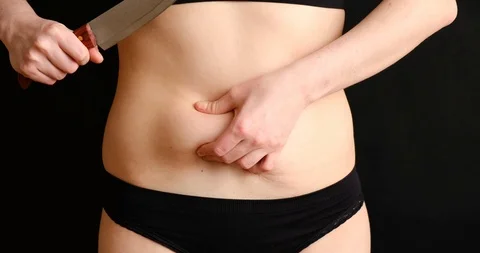 The concept of getting rid of excess weight. Girl cuts off fat deposits with Stock Footage 126364174