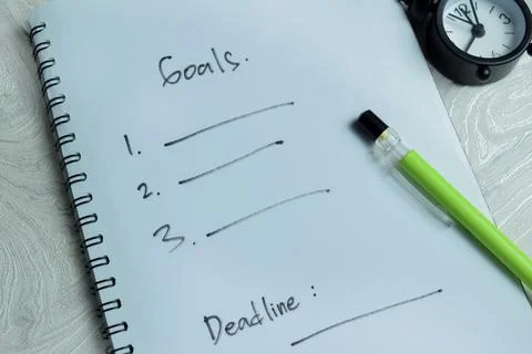 Concept of goal setting process write on book isolated on Wooden Table. Stock Photos