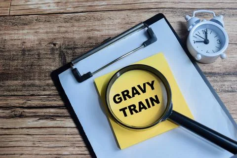 Concept of gravy train write on sticky notes isolated on Wooden Table. Stock Photos