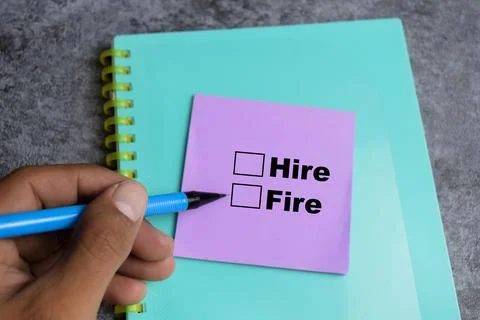 Concept of Hire or fire write on sticky notes isolated on Wooden Table. Stock Photos