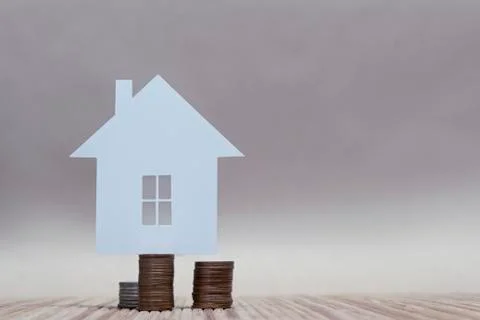The concept of home from paper on a stack of coins. Horizontal composition. 스톡 사진