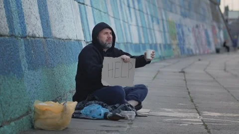 Concept of homeless poor young man sitting on the ground in the city with a Stock Footage 247188059
