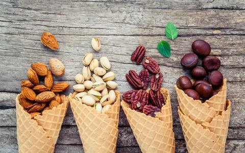 Concept for homemade various nuts ice cream. Mixed nuts in waffle cones on .. Stock Photos