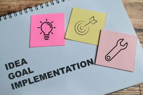 Concept of idea, goal, implementation write on book isolated on Wooden Table. Stock Photos