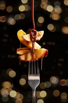 Concept image of apple fruit slices with caramel (cajeta) on metal fork. Boke Stock Photos