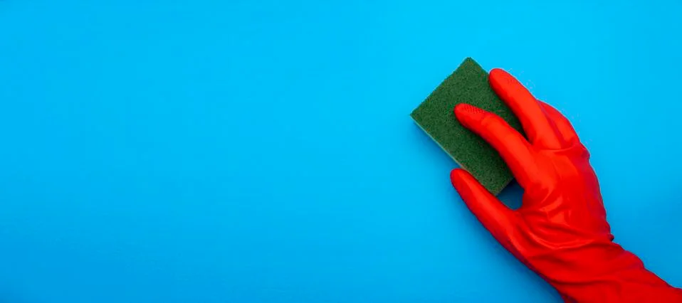 Concept image of hand in red rubber protecting glove holding sponge with gree Foto stock