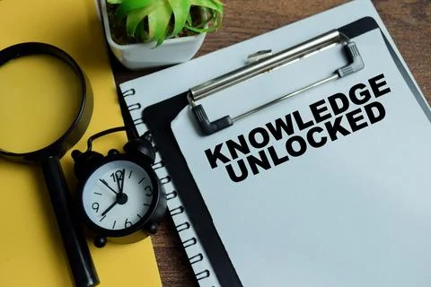Concept of knowledge unlocked write on clipboard isolated on Wooden Table. Stock Photos