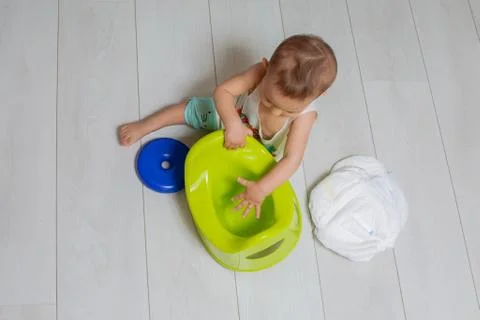The concept of learning to use the chamber-pot. little cute baby sits on the  Фото