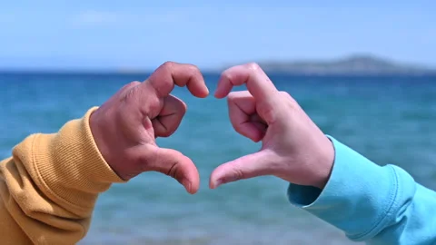Concept of love, hands of two  persons making up the heart is raised over t sea Video stock 154822505