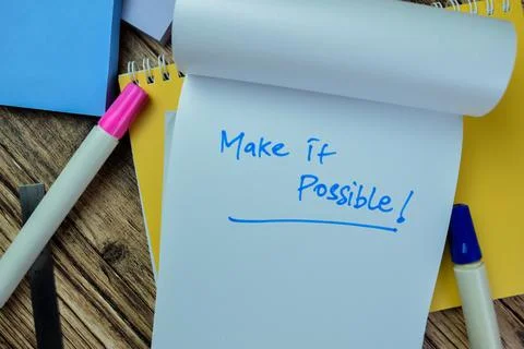 Concept of Make it Possible! write on book isolated on Wooden Table. Stock Photos