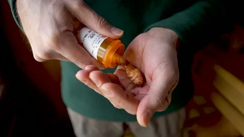 Concept - man getting fresh turmeric out of a pill bottle Stock Footage 145746208