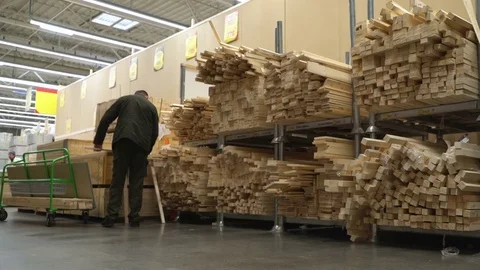 Concept men shopping in construction hypermarket. Man chooses wooden board for Stock Footage 75949127