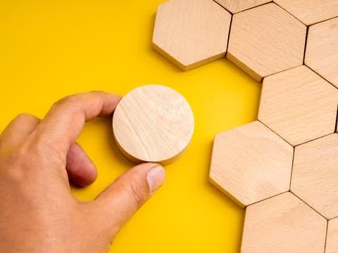 Concept of mismatch and problem solving with hand holding a round wooden pi.. Stock Photos