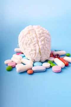 Concept model of brain surrounded by different pills on blue background Stock Photos