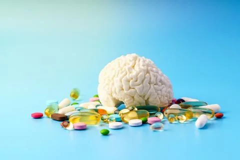 Concept model of brain surrounded by different pills on blue background Stock Photos