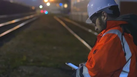 Concept of night shift. Worker in helmet using smartphone in the twilight.4k Video stock 83761026