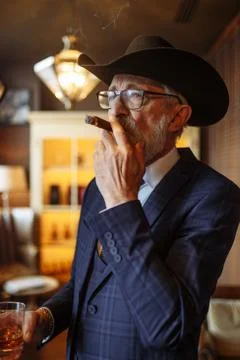 Concept of old age wisdom and experience. Old man with cigar and whiskey. Stock Photos