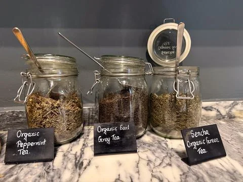 Concept of organic loose leaf teas in glass jars on marble counter for health Stock Photos